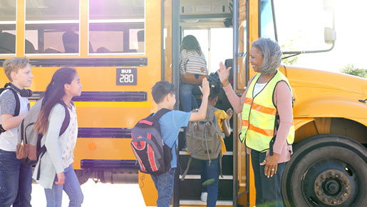 Bus driver greets children boarding bus